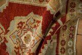 Folded vintage Oushak rug detail showing cherry red field, subtle serpent arabesques, and soft wear.