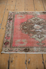 Distressed pink and sand Oushak rug, showing even wear, faint foundation, and floral motifs.