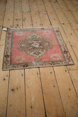Decorative distressed Oushak rug texture showing faded pink, sand, and brown floral design.
