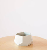 A light gray concrete air plant holder with a faceted, hexagonal geometric shape.