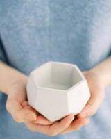 Hexagonal concrete air plant holder held in hands, revealing its light gray faceted design.