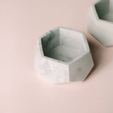The gray and white marbled interior of a faceted, hexagonal concrete planter.