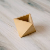 The faceted geometric shape and triangular opening of the yellow concrete air plant holder.