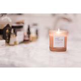 Frosted orange glass Sweet Clementine soy candle with clear label and lit wick.
