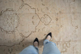 Distressed vintage Oushak rug showcasing even wear, ivory, and pale apricot vinery.