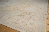 Distressed Oushak carpet with faded ivory field and pale apricot floral vinery.