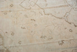 Faded vinery and blossom motifs on distressed ivory and coffee Oushak carpet.