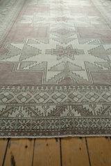 Distressed Oushak borders showcasing serrated leaves and geometric pawn motifs in mauve, ivory.