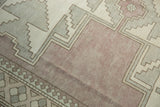 Distressed mauve Oushak rug texture with primitive geometric border pattern.