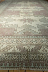 Distressed Oushak border features mauvey-beige, ivory, sea foam green pawn and leaf motifs.