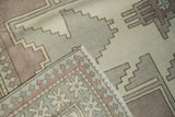 Distressed Oushak carpet corner, showcasing primitive starburst border, fringe, and pawn motifs.