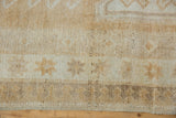 Distressed Oushak rug pile, soft beige and ivory tones, subtle geometric motifs, intact selvage.