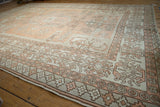 Geometric pattern on distressed Oushak carpet in pale terracotta and ivory tones.