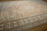 Distressed vintage Oushak rug's geometric vines, blossoms, and border in pale terracotta, ivory.