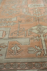 Distressed vintage Oushak carpet with geometric vine patterns in pale terracotta and ivory.