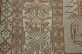 Distressed Oushak rug's geometric patterns in pale terracotta, ivory, and beige.