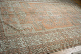 Pale terracotta, ivory geometric patterns on distressed Oushak carpet with worn knot heads.