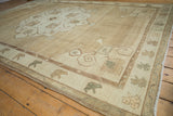 Faded ram's horn motifs on a distressed Oushak rug border in soft neutral tones.