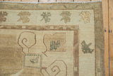 Vintage Oushak corner with ram's horn scrolls, muted green border, and abrashed neutral tones.
