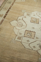 Abrashed field of the vintage Oushak rug with ram's horn stylized floral motifs in beige and coffee brown.
