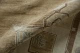 Abrashed field of a vintage Oushak rug with worn pile and beige-brown stylized motifs.