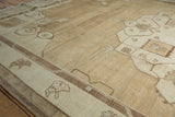 Distressed Oushak carpet edge, showing softened pale coffee brown patterns and an intact side cord.