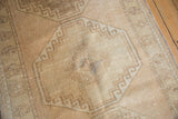 Distressed vintage Oushak runner texture, showing geometric medallion, mostly even wear, and warm beige tones.