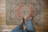 Distressed Oushak rug showcasing its stepped diamond medallion in dusty rose and silver.