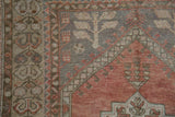 Dusty rose field, silver spandrel, and tree-of-life patterns on distressed Oushak rug.