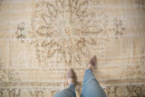 Distressed Oushak carpet, faded ivory medallion, blush vine motifs, and even wear.