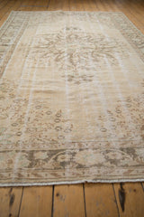 Distressed vintage Turkish Oushak carpet with faded starburst medallion and pale rose pattern.