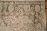 Corner detail of a distressed Oushak rug, showing worn ivory, brown, and green floral motifs.