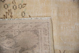 Distressed vintage Oushak carpet: close-up of worn ivory pile, short fringe, and woven back foundation.
