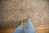 Vintage distressed Oushak rug with faded diamond and hook motifs in neutral tones.
