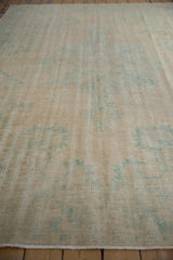 Floor-level view of a distressed Oushak carpet showing its textured, worn low pile.