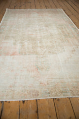 Oushak rug close-up: worn texture, visible foundation, and subtle blush, blue hues.