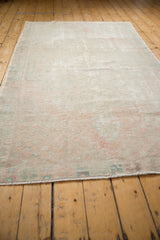 Distressed Oushak rug edge, foundation showing through, with blush, ivory, and pale blue.