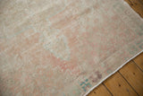 Distressed Oushak rug texture with worn pile in faded blush, ivory, and pale blue.