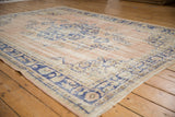 Distressed Oushak pile texture, featuring a faded pale rose field and cobalt blue patterns.