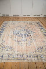 Distressed Oushak rug with faded pale rose field and curvilinear cobalt blue florals.