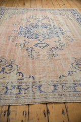 Distressed vintage Oushak rug bottom border, cobalt blue motifs on dusty rose beige, visible wear.