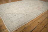 Distressed vintage Oushak rug's faded floral corner spandrel and meandering border.