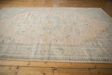 Texture of distressed Oushak rug with faded ivory and soft teal floral border.