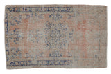 Vintage distressed Oushak rug with a faded floral medallion in dusty rose, cobalt blue, and antique ivory.
