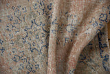 Detail of a distressed Turkish Oushak rug showing worn pile and exposed knot heads.
