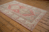 Distressed Oushak rug with pale ruby red grapefruit field and ivory geometric border.
