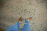 Distressed Oushak carpet with mostly even wear, faded ivory, pink, and charcoal patterns underfoot.