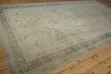 Distressed vintage Oushak carpet, muted ivory field, worn texture, and charcoal spandrel detail.
