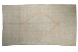 A distressed vintage Oushak carpet with a tone-on-tone medallion and corner spandrels in pale apricot and sand.
