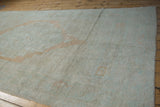 Low-angle view of a distressed Oushak carpet showing its soft, low-pile texture and muted colors.